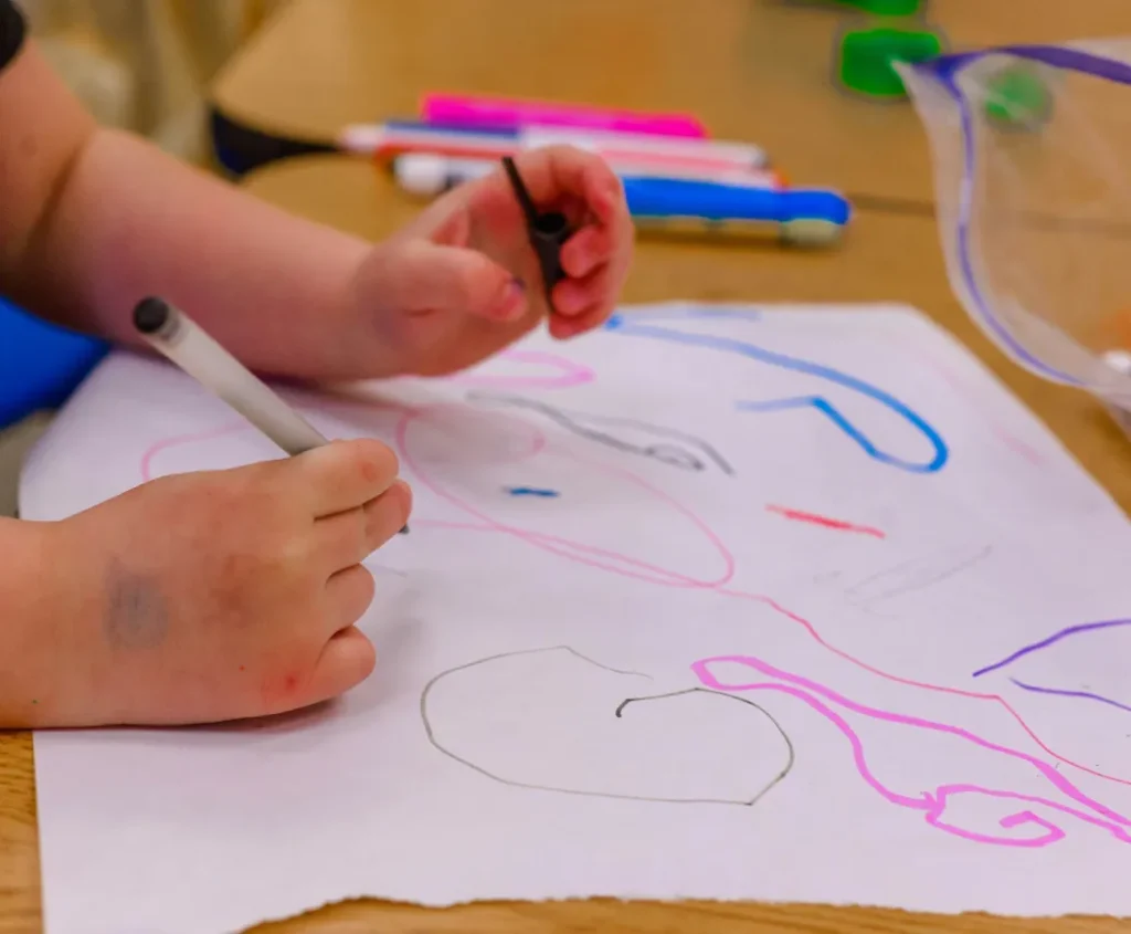 Child drawing with colorful markers at a table