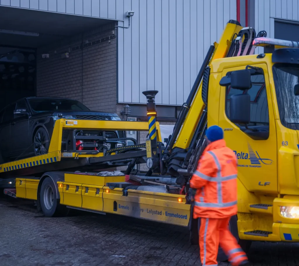 Tow truck operator loading a vehicle outside a garage