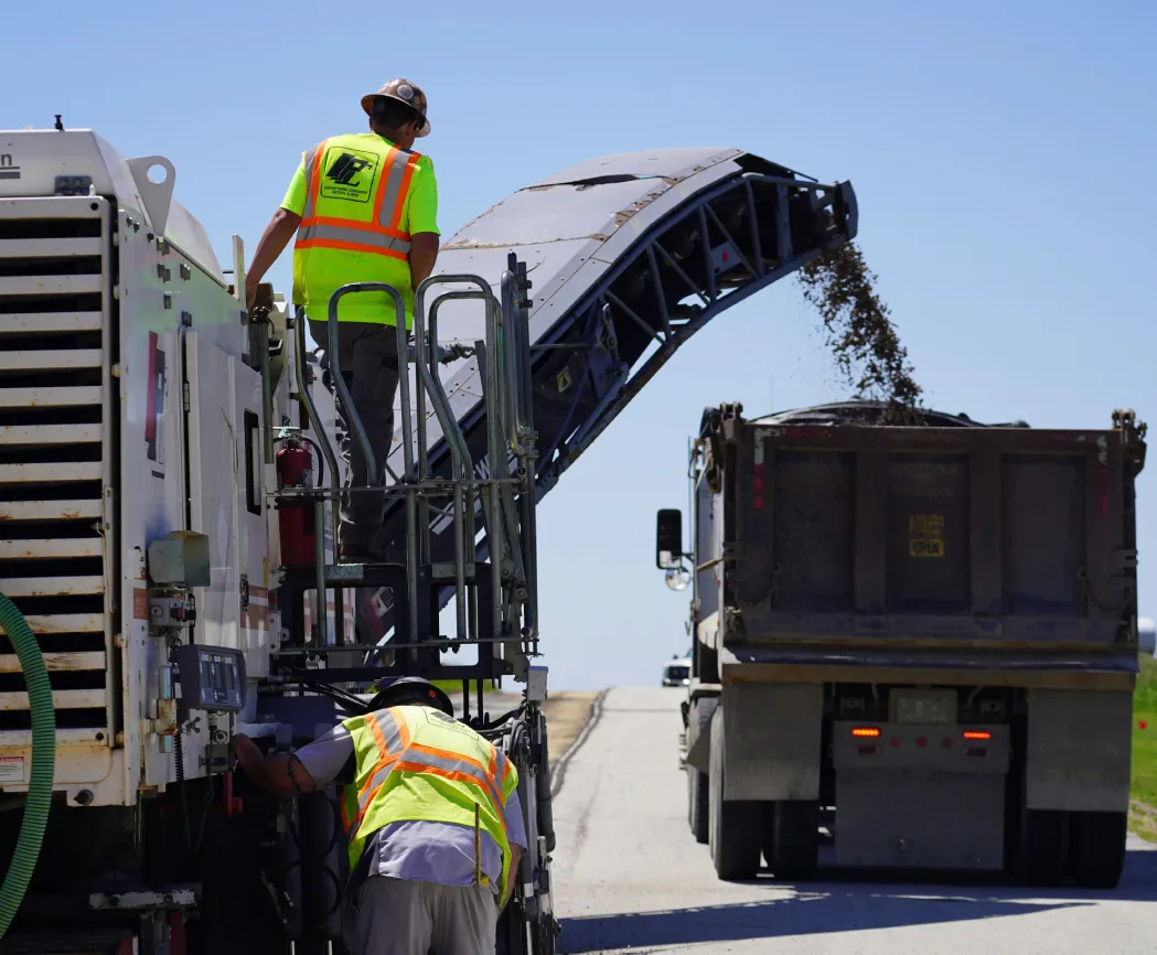 Road workers loading debris into a dump truck