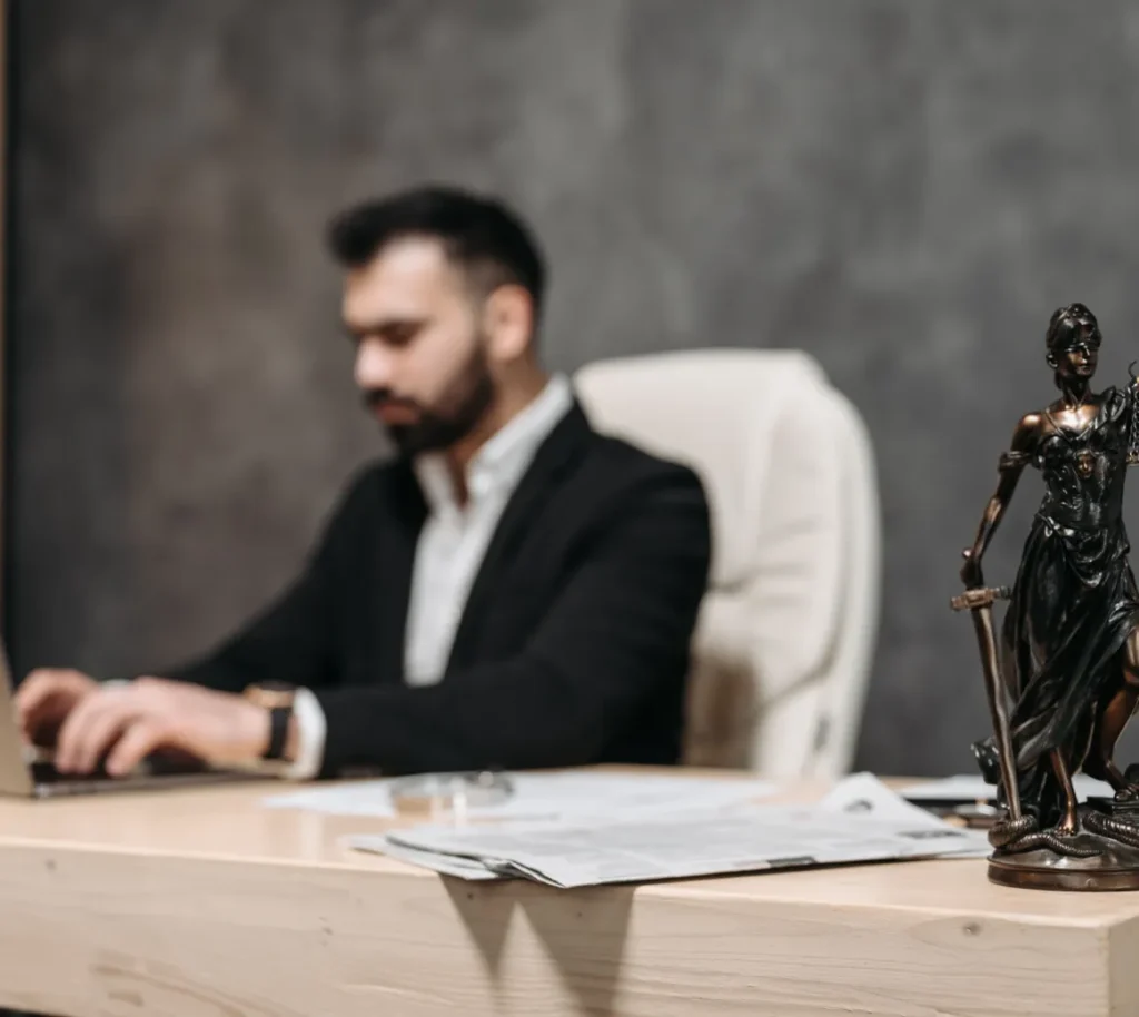 Lawyer working at a desk beside a Lady Justice statue