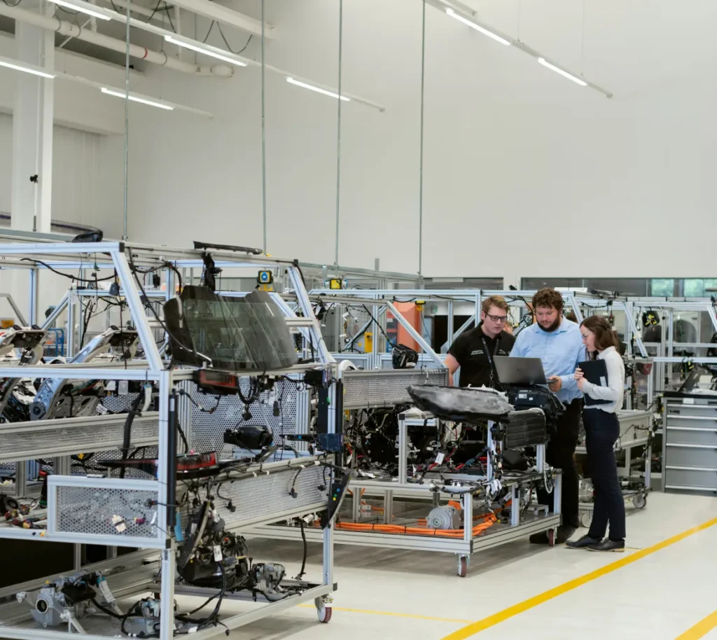 Manufacturing team reviewing a laptop beside production equipment