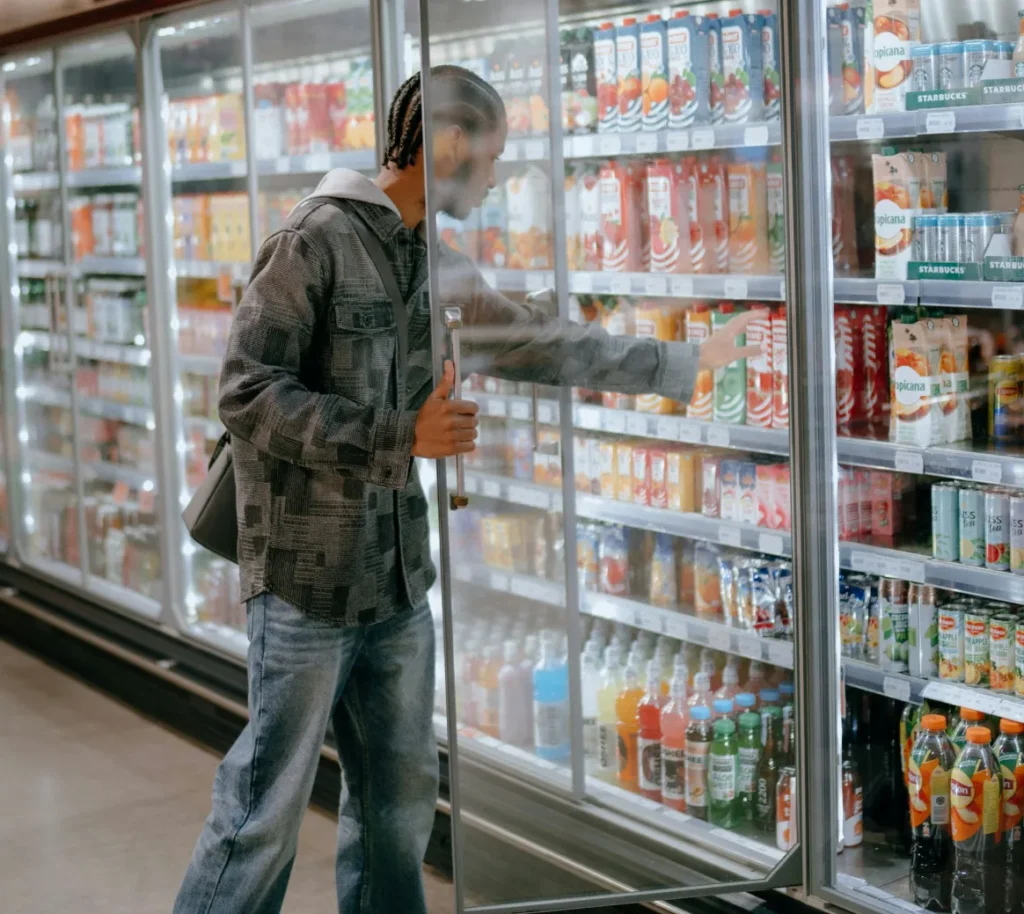 Customer selecting a drink from a refrigerated store display