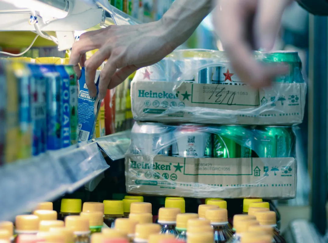 Customer selecting canned beverages from a store refrigerator
