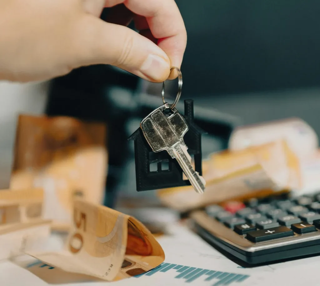 House key held above money and a calculator